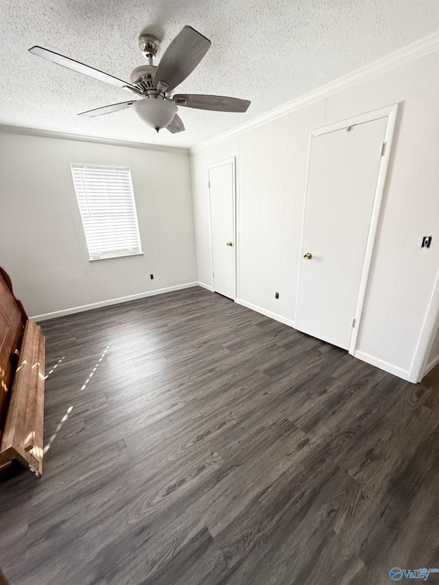 unfurnished bedroom with a textured ceiling, dark wood-type flooring, ceiling fan, and ornamental molding