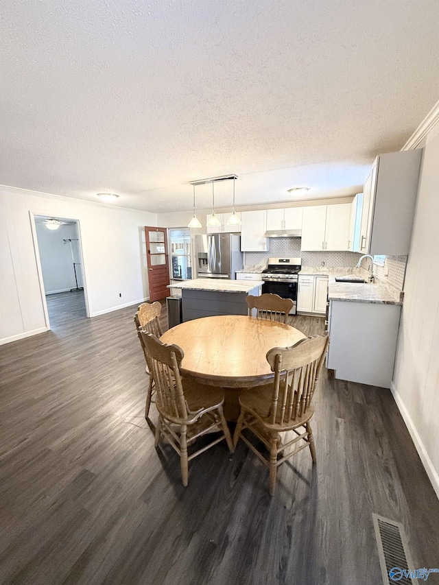 dining space with dark hardwood / wood-style floors, sink, ornamental molding, and a textured ceiling