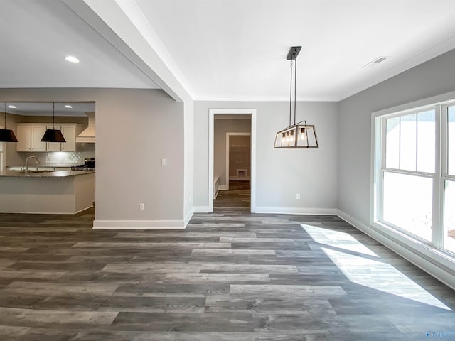 unfurnished dining area featuring plenty of natural light, dark hardwood / wood-style floors, ornamental molding, and sink