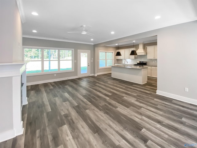 unfurnished living room with crown molding, dark wood-type flooring, ceiling fan, and sink