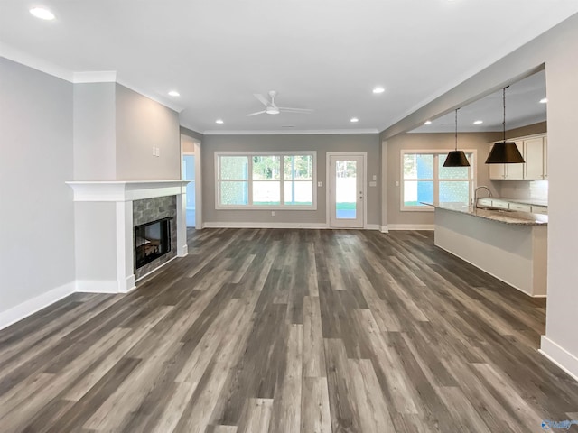 unfurnished living room featuring dark wood-type flooring, ceiling fan, a fireplace, and sink