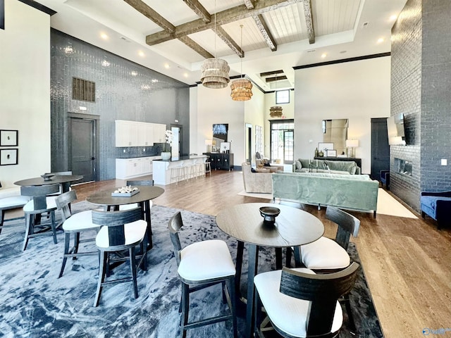119 Moss Brook Ln, Madison, AL 35757 - dining area with a towering ceiling, wood finished floors, beamed ceiling, a chandelier, and a fireplace