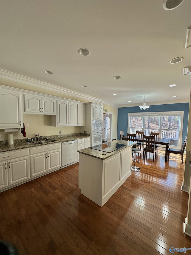 kitchen with white cabinetry, hardwood / wood-style flooring, a center island, crown molding, and white appliances