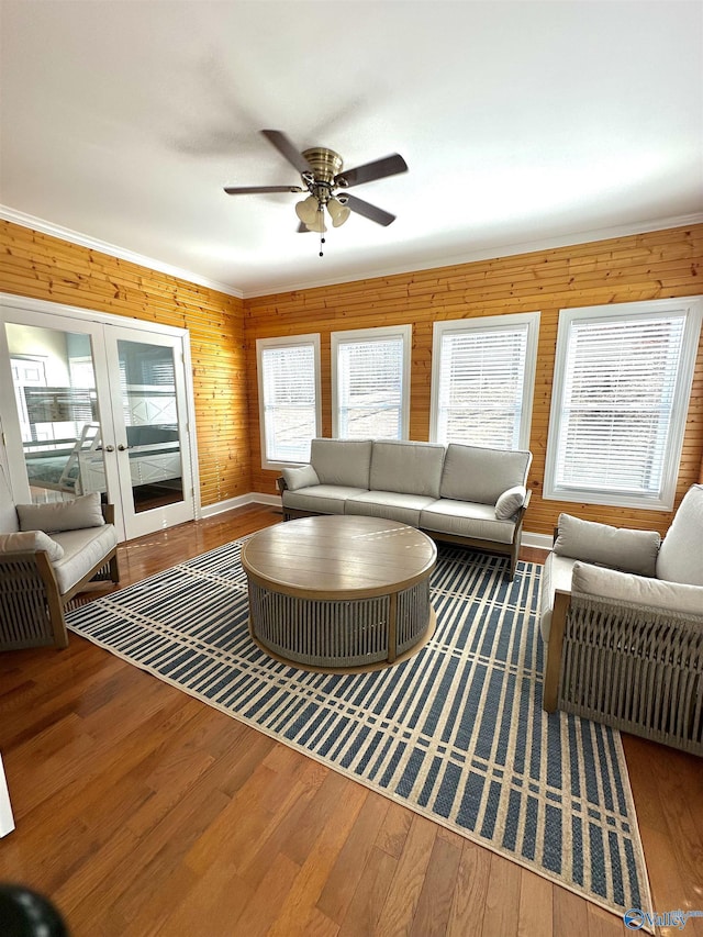 living room with hardwood / wood-style flooring, ceiling fan, wooden walls, and french doors