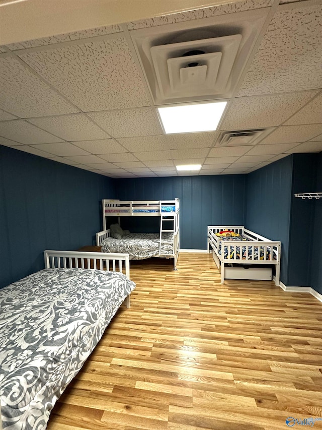 bedroom featuring wood-type flooring and a drop ceiling