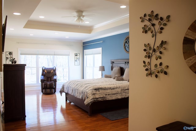 bedroom featuring crown molding, wood-type flooring, ceiling fan, and a tray ceiling