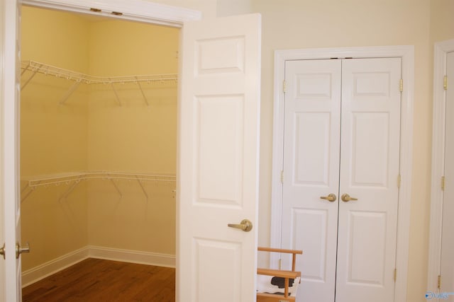 walk in closet with dark hardwood / wood-style flooring