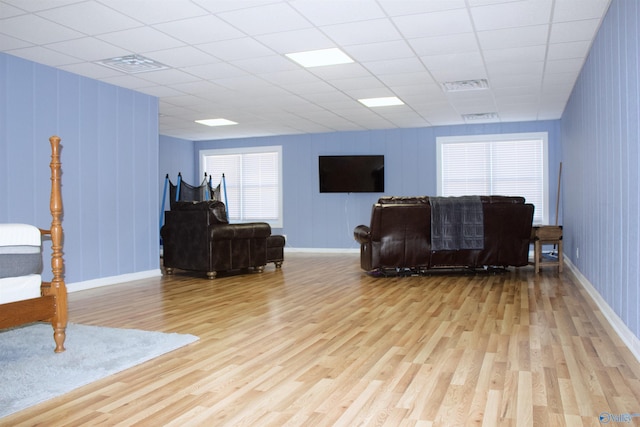 living room featuring a paneled ceiling and light hardwood / wood-style flooring