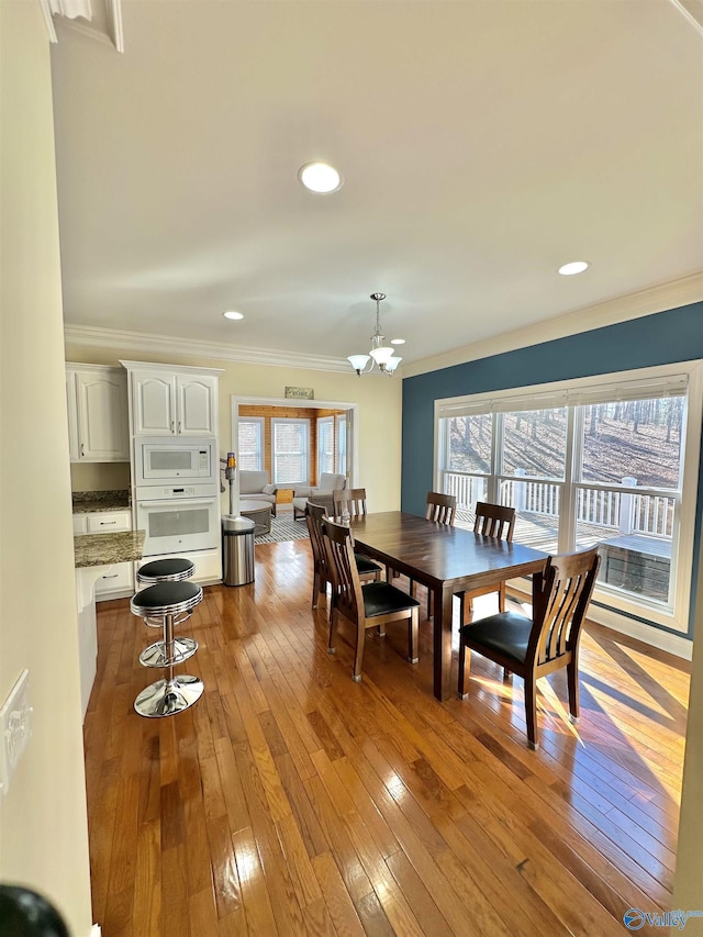 dining room with ornamental molding, a chandelier, and light hardwood / wood-style floors