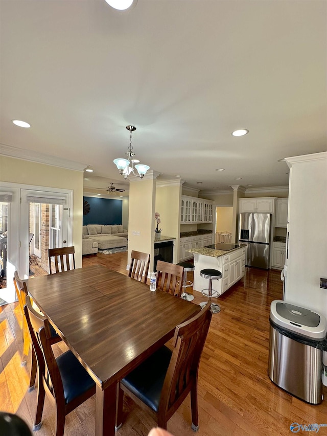 dining space featuring ornate columns, ornamental molding, dark wood-type flooring, and a notable chandelier