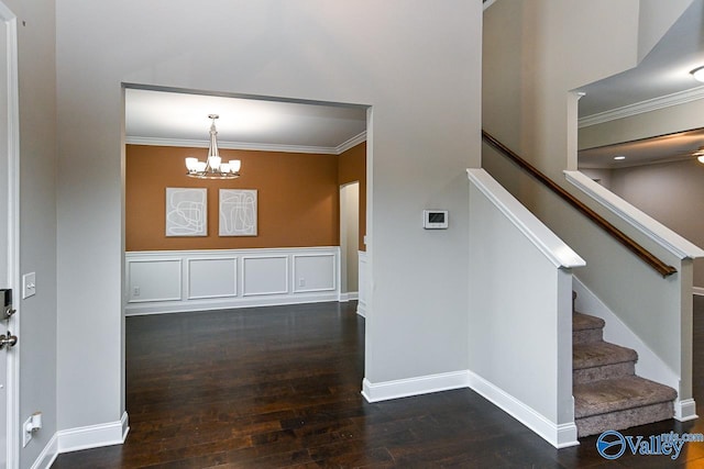 entrance foyer with ornamental molding, dark wood-type flooring, and an inviting chandelier