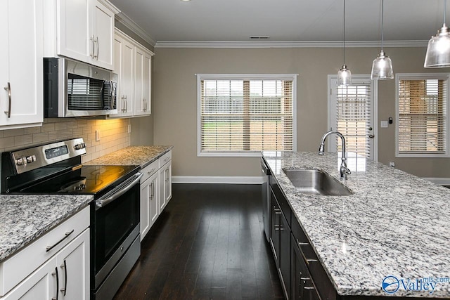 kitchen featuring sink, an island with sink, pendant lighting, white cabinets, and appliances with stainless steel finishes