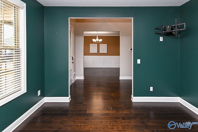 corridor with ornamental molding, an inviting chandelier, and dark wood-type flooring