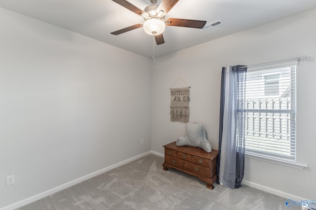 spare room featuring visible vents, light carpet, a wealth of natural light, and ceiling fan