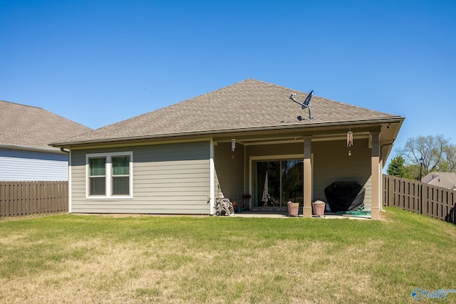 rear view of house featuring a lawn, a fenced backyard, and roof with shingles