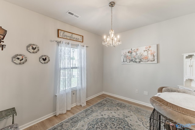 dining space with baseboards, light wood-style flooring, visible vents, and an inviting chandelier