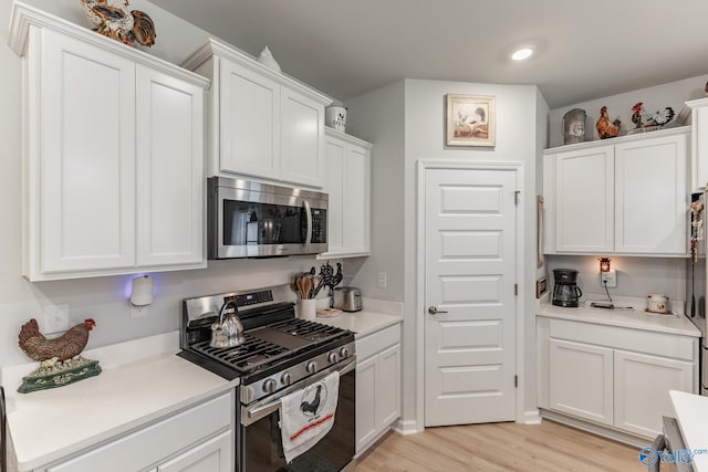 kitchen with appliances with stainless steel finishes, white cabinetry, and light countertops