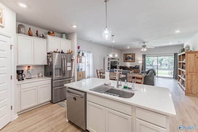 kitchen with light wood-type flooring, stainless steel appliances, white cabinets, and open floor plan