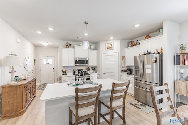 kitchen with light countertops, stainless steel appliances, light wood finished floors, and a sink