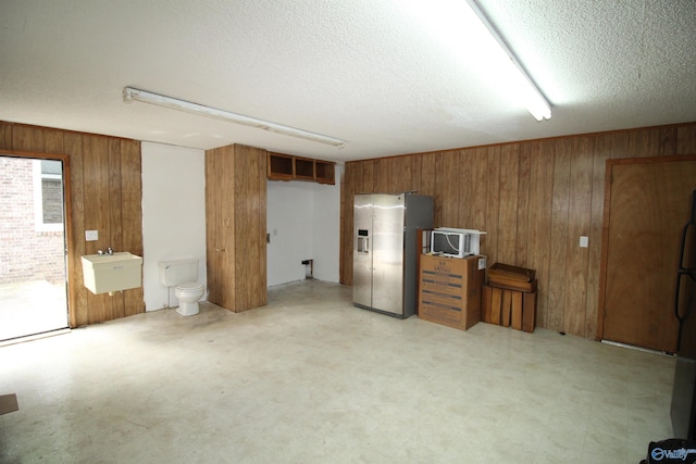 195 Holly Lynn Ln, Hazel Green, AL 35750 - below grade area featuring stainless steel refrigerator with ice dispenser, wooden walls, a textured ceiling, light floors, and a sink