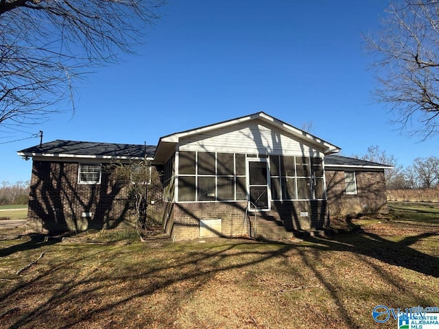 rear view of property featuring a sunroom and a lawn