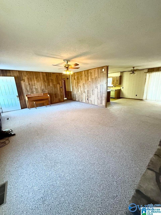 unfurnished living room with ceiling fan, carpet floors, and a textured ceiling