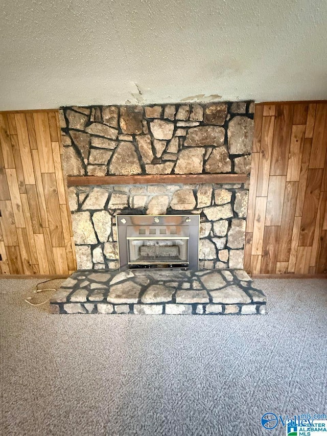 interior details with a textured ceiling, a fireplace, and wood walls