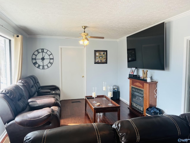 living room featuring ornamental molding, dark wood-type flooring, ceiling fan, and a textured ceiling