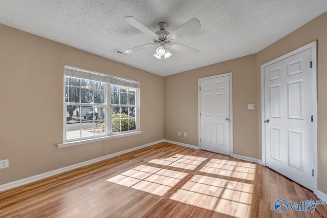 unfurnished bedroom featuring a textured ceiling, ceiling fan, and light wood-type flooring