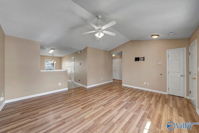 unfurnished living room with a textured ceiling, light hardwood / wood-style flooring, lofted ceiling, and ceiling fan with notable chandelier