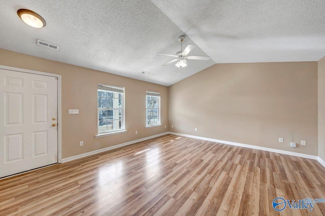 interior space with lofted ceiling, a textured ceiling, and light wood-type flooring