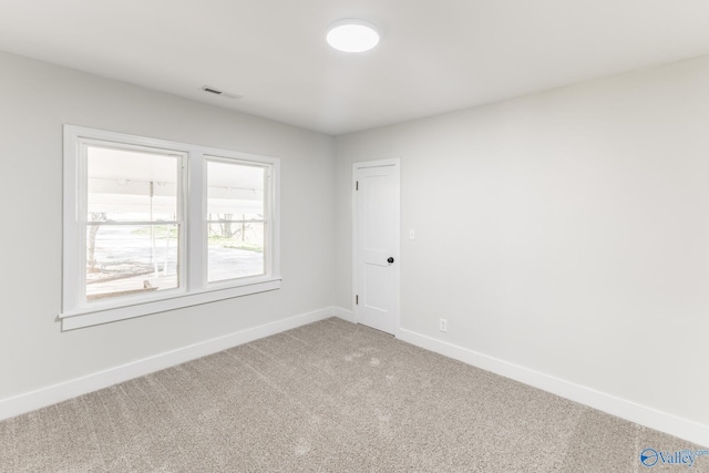 empty room with baseboards, visible vents, and light carpet