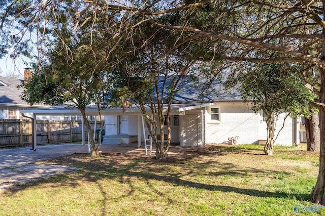 view of front of property with a carport, brick siding, a front lawn, and fence