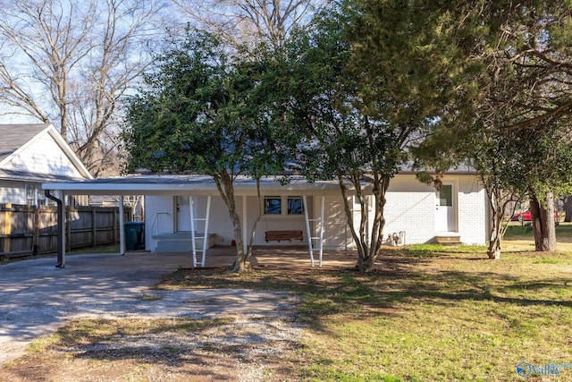 ranch-style home featuring a front yard, fence, entry steps, a carport, and brick siding