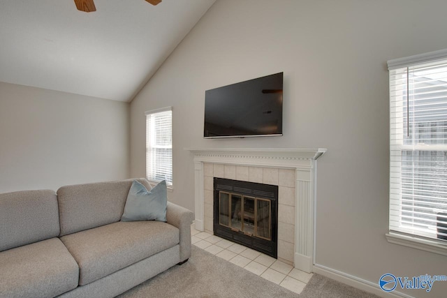 living room featuring lofted ceiling, a wealth of natural light, a tiled fireplace, and light colored carpet