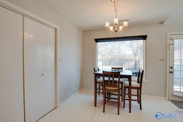 dining area featuring a chandelier, light floors, a textured ceiling, and baseboards