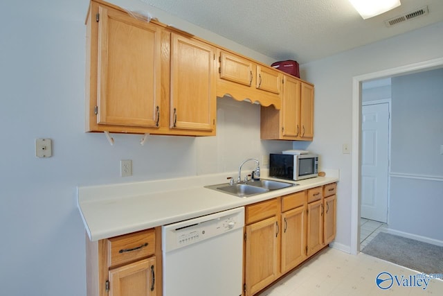 kitchen with a sink, visible vents, light countertops, dishwasher, and stainless steel microwave