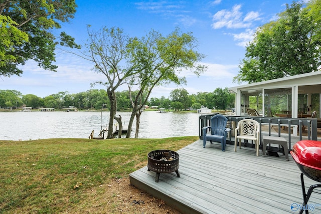 wooden deck featuring a yard, an outdoor fire pit, a water view, and a sunroom