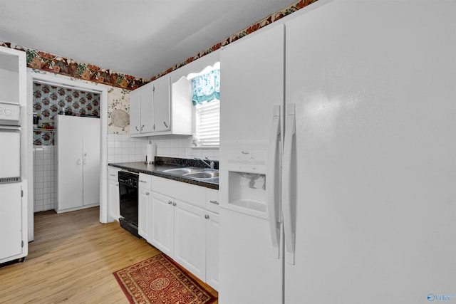 kitchen featuring a sink, light wood-type flooring, dark countertops, wallpapered walls, and white appliances
