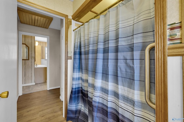 bathroom with baseboards, wood finished floors, and curtained shower