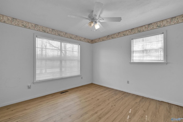 spare room featuring baseboards, wood finished floors, visible vents, and ceiling fan