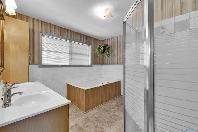bathroom featuring a bath, tile walls, tile patterned floors, and a sink