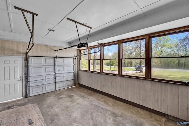 garage featuring baseboards, wood walls, and a garage door opener