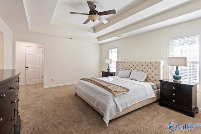 bedroom with ceiling fan, a raised ceiling, and light colored carpet