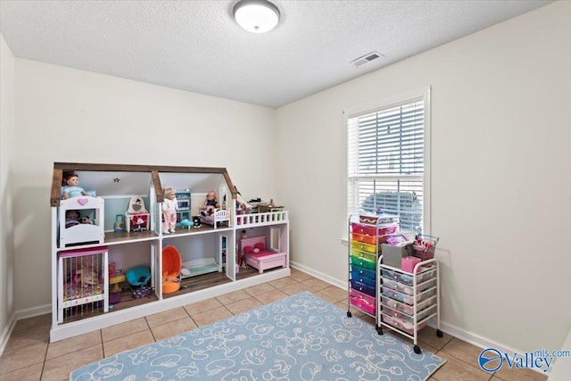 recreation room featuring tile patterned flooring and a textured ceiling