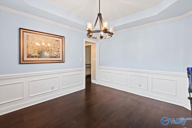 unfurnished room with an inviting chandelier, dark wood-type flooring, and a tray ceiling