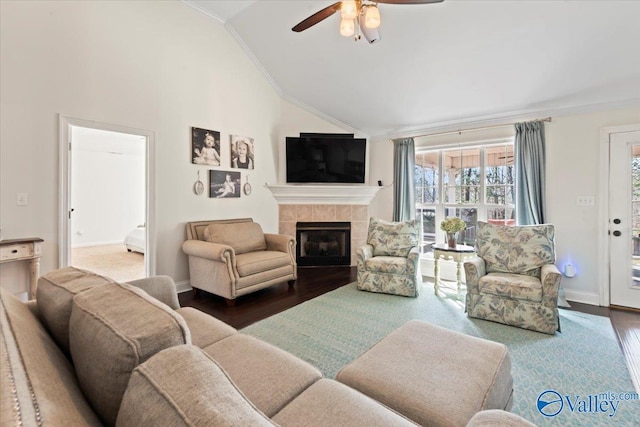 living room with lofted ceiling, a tile fireplace, ceiling fan, ornamental molding, and dark hardwood / wood-style flooring