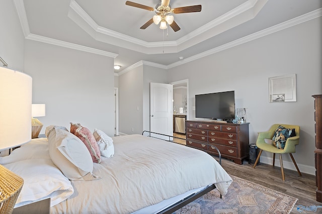 bedroom with crown molding, ceiling fan, wood-type flooring, and a raised ceiling