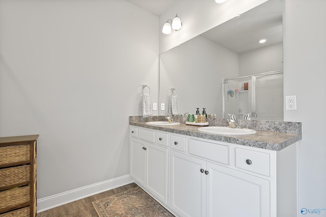 bathroom featuring wood-type flooring, a shower with door, and vanity