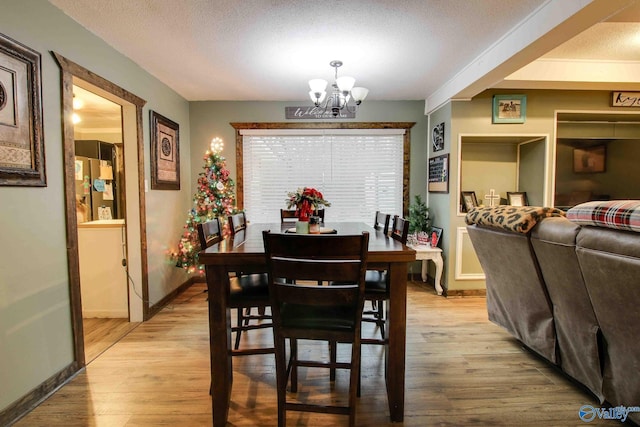 dining space featuring an inviting chandelier, a textured ceiling, and light hardwood / wood-style flooring